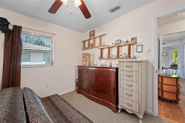 bedroom with ceiling fan, a textured ceiling, and light carpet