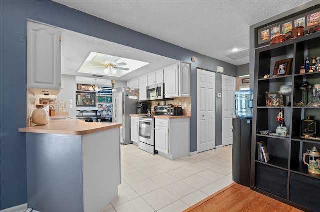 kitchen with white cabinets, stainless steel appliances, and ceiling fan