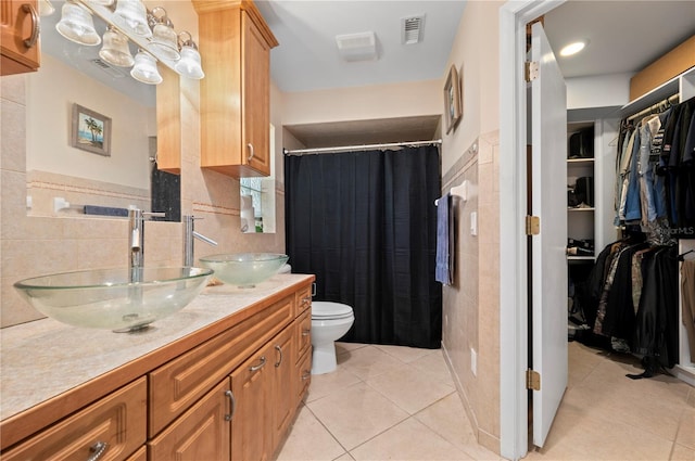 bathroom with tile walls, tile patterned flooring, vanity, and toilet