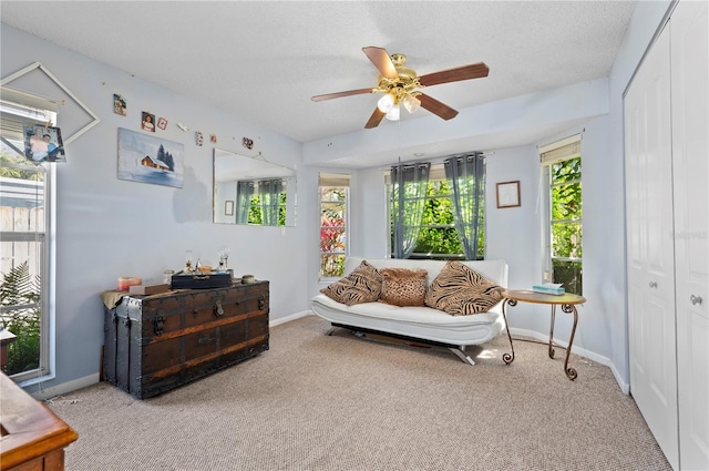 living area featuring ceiling fan, a healthy amount of sunlight, light carpet, and a textured ceiling