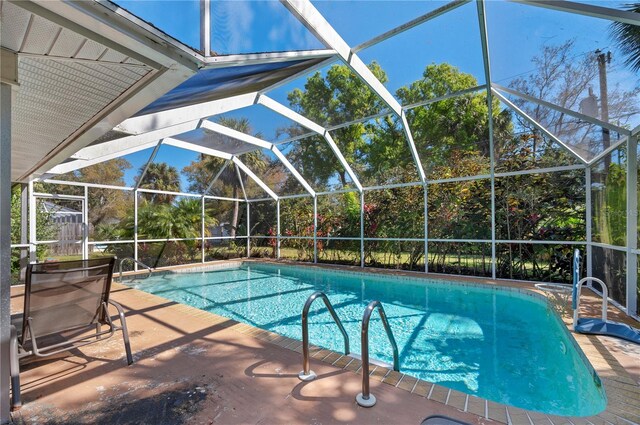 view of pool with glass enclosure and a patio