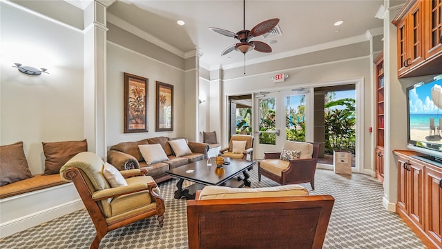 living room featuring ceiling fan, light colored carpet, crown molding, french doors, and decorative columns