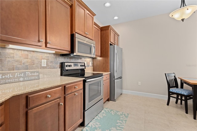 kitchen featuring decorative light fixtures, tasteful backsplash, light stone countertops, stainless steel appliances, and light tile patterned floors