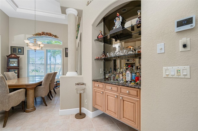 bar featuring a chandelier, light tile floors, dark stone countertops, and crown molding