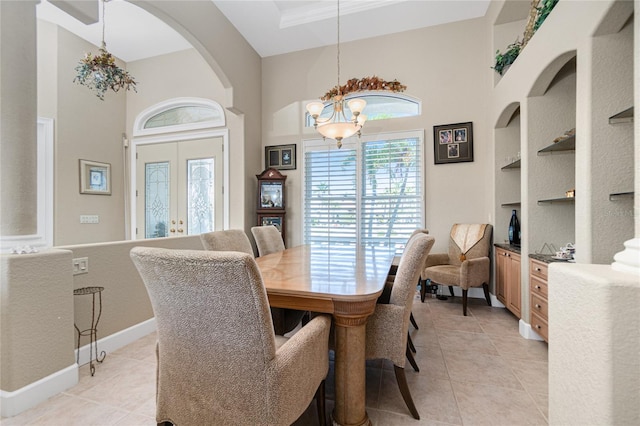 tiled dining room featuring built in shelves, french doors, a chandelier, and a towering ceiling