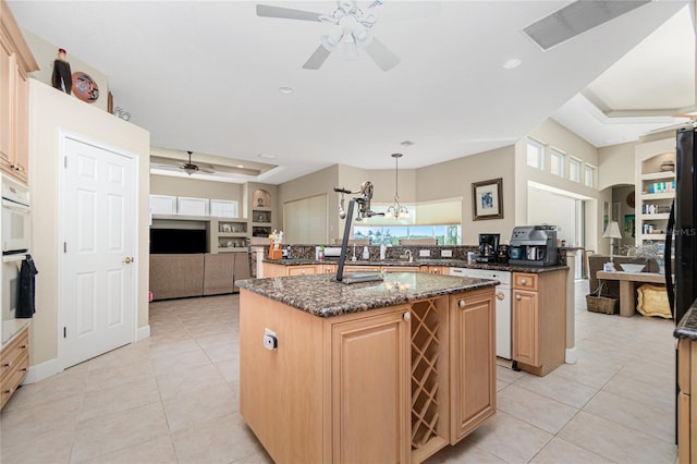 kitchen with a center island with sink, ceiling fan with notable chandelier, hanging light fixtures, and oven