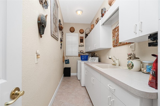 laundry room featuring washing machine and dryer, cabinets, sink, and light tile floors