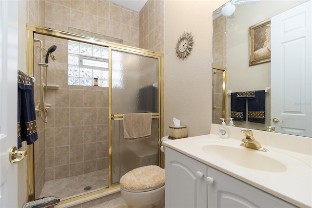 bathroom featuring toilet, ceiling fan, an enclosed shower, and vanity