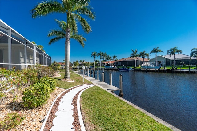 dock area featuring a lawn, a water view, and a lanai