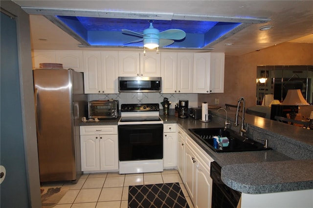 kitchen with white cabinetry, ceiling fan, a tray ceiling, sink, and appliances with stainless steel finishes