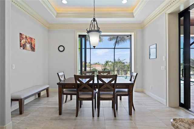 tiled dining space with crown molding and a tray ceiling