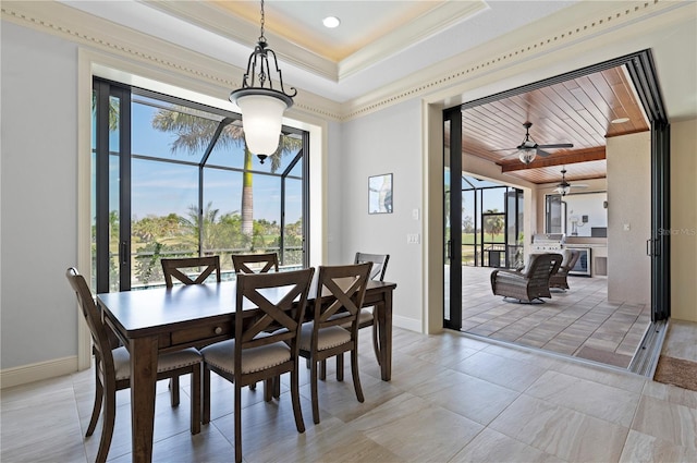 tiled dining space featuring ornamental molding, ceiling fan, and a tray ceiling