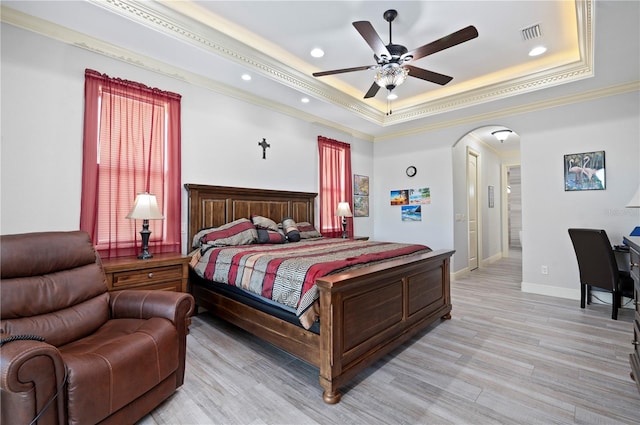 bedroom with a raised ceiling, light hardwood / wood-style floors, crown molding, and ceiling fan