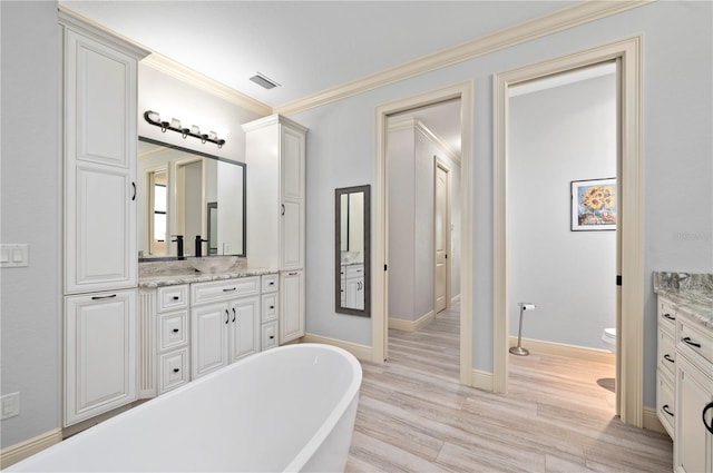 bathroom with vanity, hardwood / wood-style floors, a washtub, toilet, and crown molding