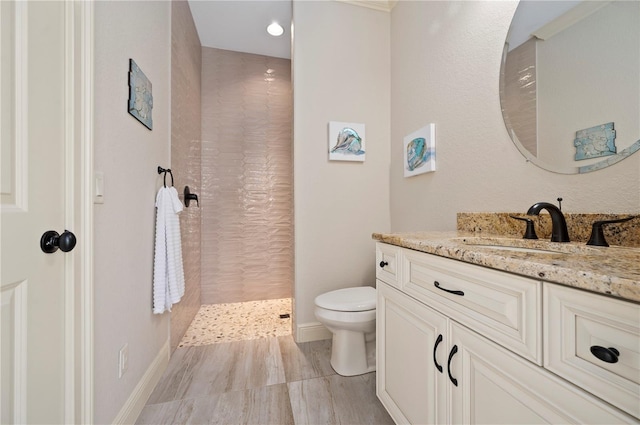 bathroom with vanity, tile floors, toilet, and tiled shower