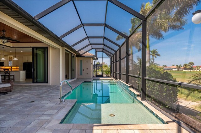 view of swimming pool with a patio area, ceiling fan, and glass enclosure