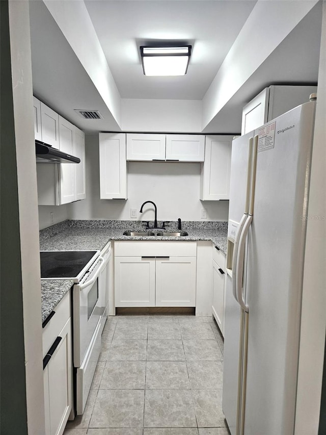 kitchen with light tile patterned floors, white cabinetry, white appliances, light stone countertops, and sink