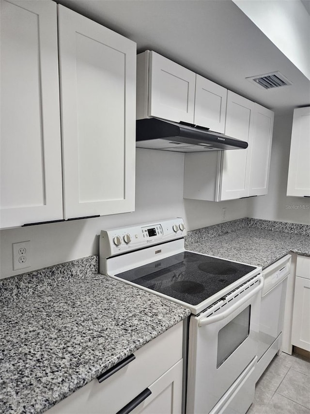 kitchen with light tile patterned floors, white cabinets, light stone counters, and white appliances