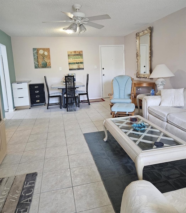 living room featuring ceiling fan, light tile patterned flooring, and a textured ceiling