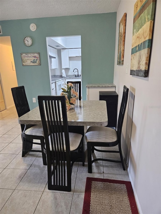 dining room with a textured ceiling, light tile patterned floors, and sink