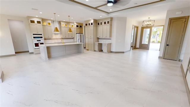 kitchen with an island with sink, pendant lighting, light tile floors, ceiling fan with notable chandelier, and tasteful backsplash