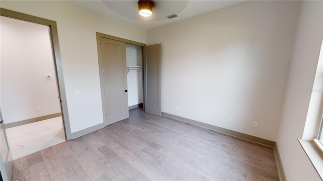 unfurnished bedroom featuring light hardwood / wood-style floors, a closet, and ceiling fan