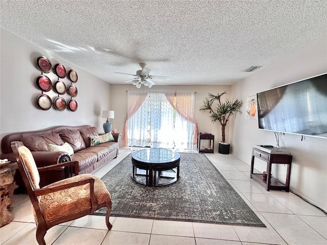 living room with ceiling fan, light tile patterned floors, and a textured ceiling