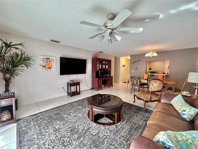 tiled living room featuring a textured ceiling and ceiling fan with notable chandelier