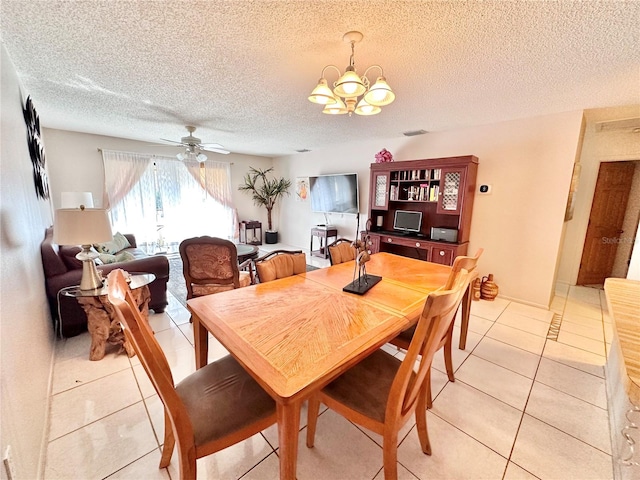 tiled dining room with ceiling fan with notable chandelier and a textured ceiling