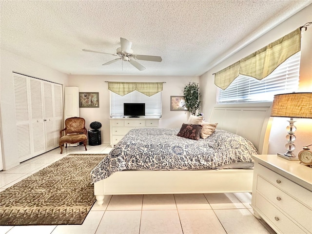 tiled bedroom featuring a textured ceiling, ceiling fan, and a closet