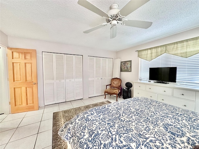 bedroom featuring multiple closets, a textured ceiling, light tile patterned floors, and ceiling fan