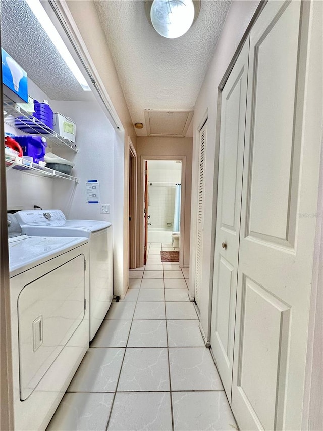 laundry room featuring washing machine and clothes dryer, light tile patterned floors, and a textured ceiling