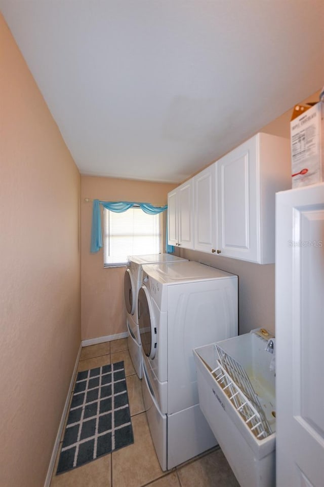 washroom featuring light tile floors, cabinets, and washing machine and dryer