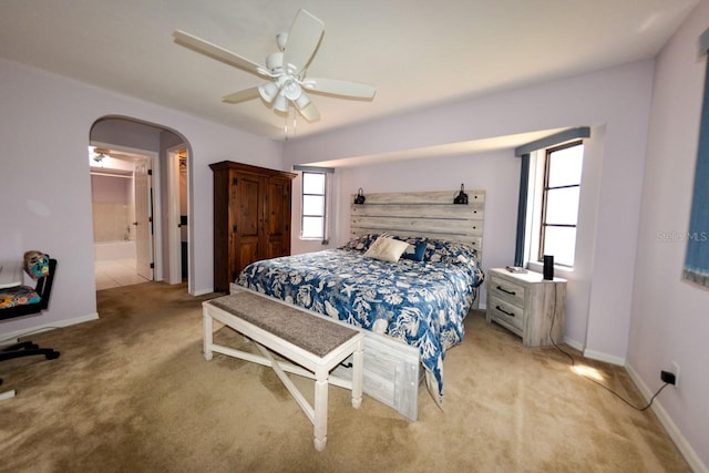 carpeted bedroom with ensuite bath and ceiling fan