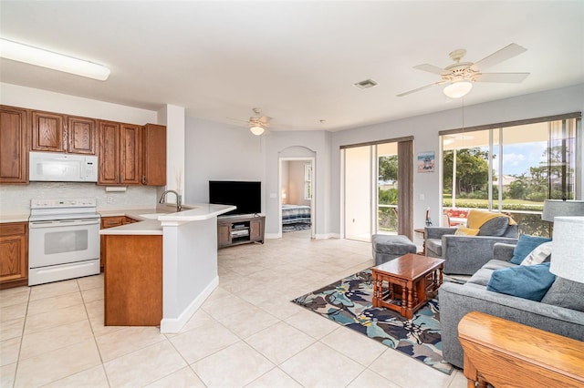 kitchen featuring white appliances, decorative backsplash, ceiling fan, light tile patterned floors, and kitchen peninsula