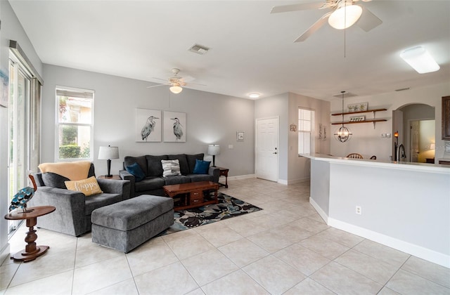 living room featuring ceiling fan with notable chandelier, light tile patterned flooring, and sink