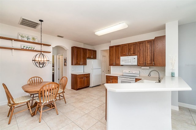 kitchen featuring kitchen peninsula, white appliances, sink, pendant lighting, and a chandelier