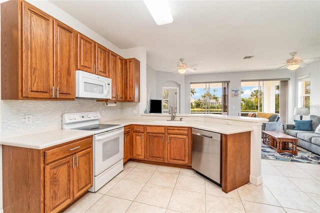 kitchen featuring sink, white appliances, kitchen peninsula, and light tile patterned floors