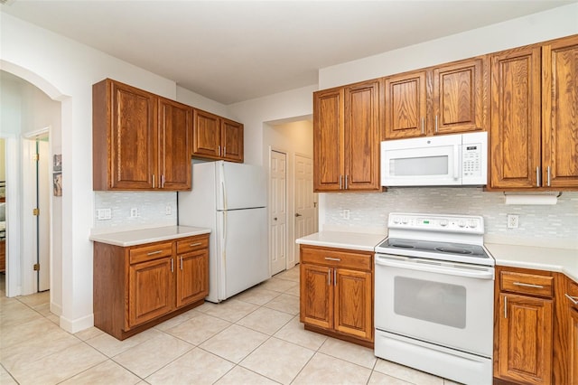 kitchen with tasteful backsplash, light tile patterned floors, and white appliances