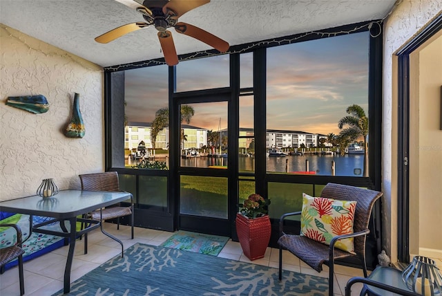 sunroom / solarium featuring a water view and ceiling fan