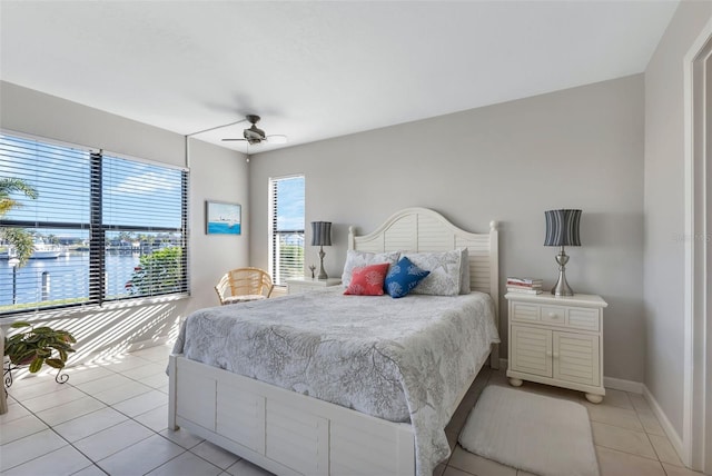 bedroom with ceiling fan, a water view, and light tile floors