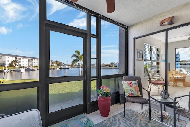 sunroom featuring ceiling fan and a water view