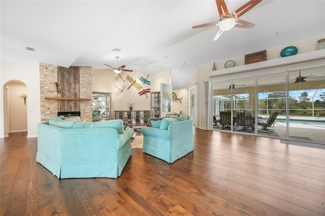 living room with high vaulted ceiling, dark hardwood / wood-style floors, ceiling fan, and a stone fireplace