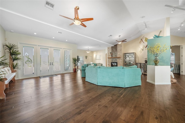 unfurnished living room featuring ceiling fan, rail lighting, a fireplace, dark wood-type flooring, and lofted ceiling