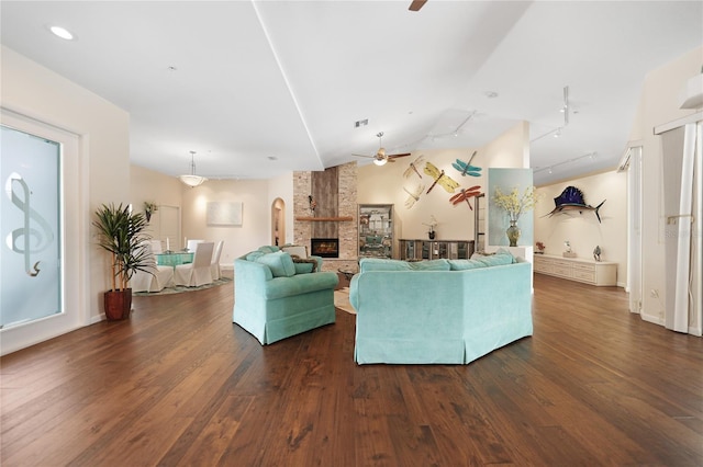 living room featuring dark hardwood / wood-style flooring, vaulted ceiling, ceiling fan, and a fireplace