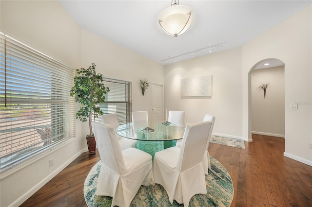 dining area with dark hardwood / wood-style floors and track lighting