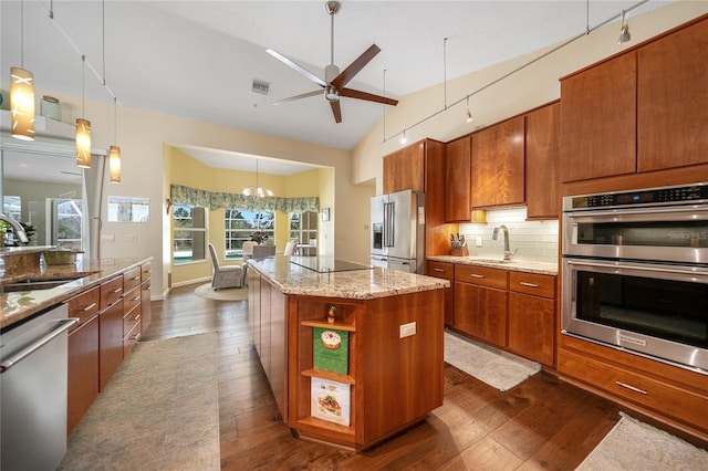 kitchen featuring stainless steel appliances, a kitchen island, ceiling fan with notable chandelier, tasteful backsplash, and dark hardwood / wood-style flooring