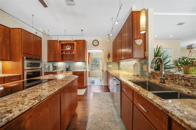 kitchen featuring light stone countertops, rail lighting, tasteful backsplash, appliances with stainless steel finishes, and sink