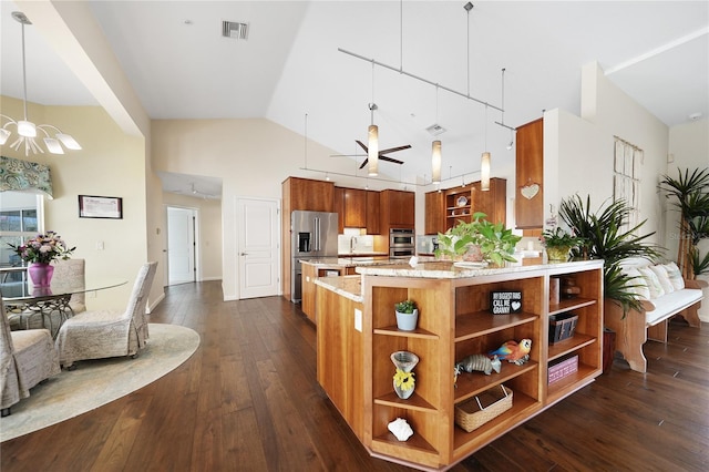 kitchen with light stone countertops, dark wood-type flooring, ceiling fan with notable chandelier, high vaulted ceiling, and stainless steel appliances