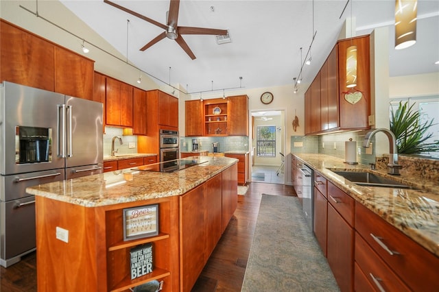 kitchen featuring sink, ceiling fan, light stone counters, backsplash, and a center island